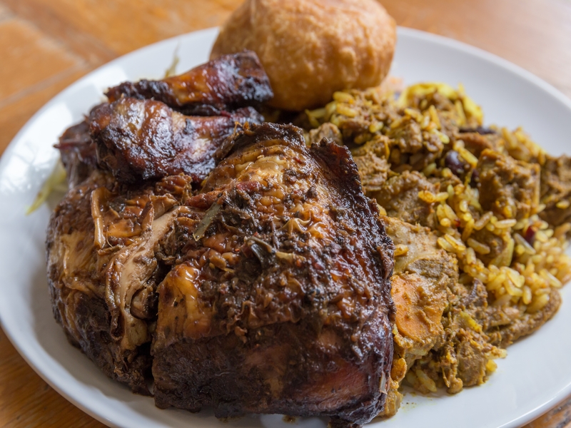 Traditional Jamaican curried goat, jerk chicken and fried dumpling with rice and peas